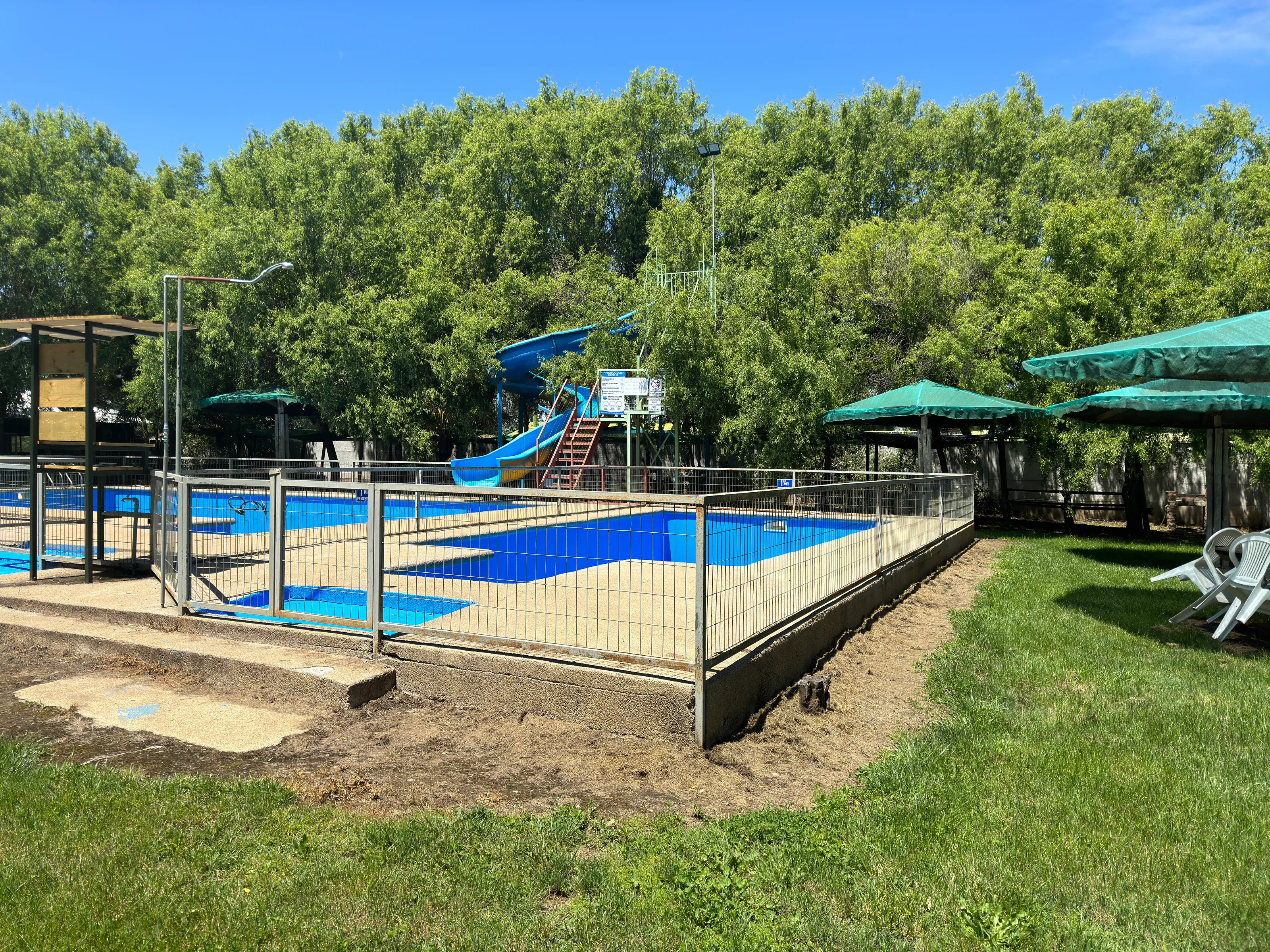 Piscinas y tobogán del parque rodeados de árboles y áreas verdes